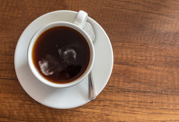 White cup with coffee on brown wooden table