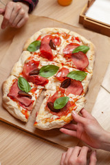 Woman eating roman square pizza with pastrami and sweet plum, holding a piece with a hand, for dinner in a cafe