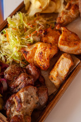 Macro close up of assorted grilled meat snacks: chicken, beef and lamb kebab, roasted pork shish kebab, served with coleslaw
