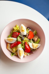 Top view of traditional american cobb salad with chopped avocado, tomatoes, hard boiled egg, roasted chicken and greens for a healthy lunch