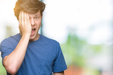 Young handsome man wearing blue t-shirt over isolated background covering one eye with hand with confident smile on face and surprise emotion.