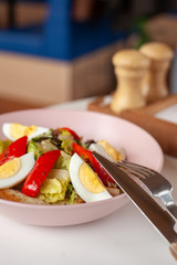 Traditional american cobb salad with chopped avocado, tomatoes, hard boiled egg, roasted chicken and greens for a healthy lunch on a blurred background