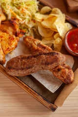 Close up of beef kebab, made on coal grill, served with other bbq meat treats, coleslaw and chips on a wooden tray