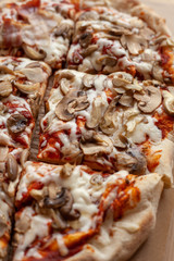 Macro close up of a roman square pizza on thick dough with champignons and a lot of cheese, served on craft paper