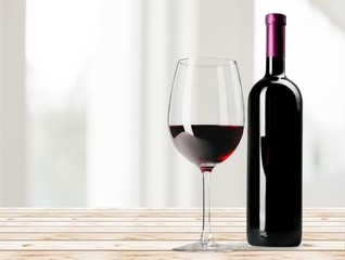 Fototapeta Red wine glass on wooden desk at wall background obraz