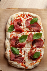 Top view of roman square pizza on a thick dough with mozzarella, pastrami, sweet plum and basil...