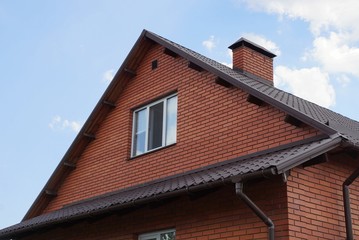 Fototapeta na wymiar brown loft brick house with a window against the sky