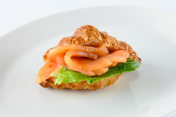 Freshly baked french croissant with cream cheese, green leaves and smoked salmon, isolated on white