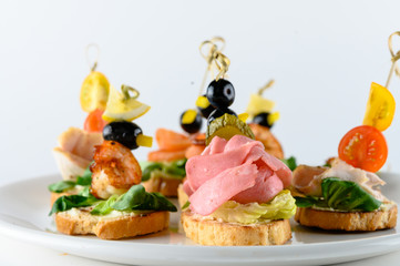 Variety of cold appetizers for party buffet or banquet ? different states canapes on skewers with greens, meat, cheese and seafood isolated on white