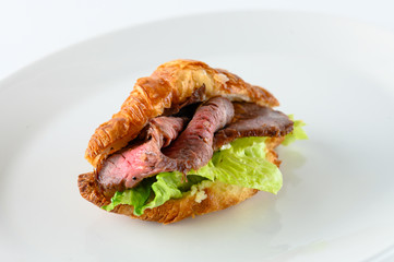 Fresh french croissant with greens and smoked pork meat as a perfect appetizer isolated on white