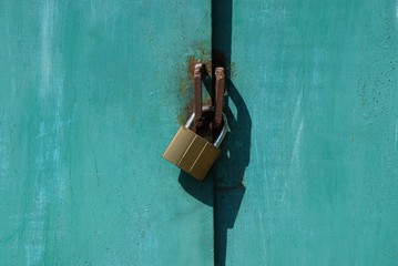 brown padlock hanging on green metal gate outside