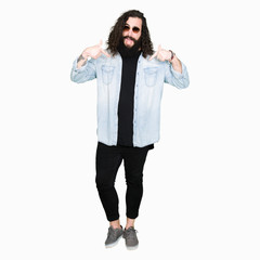 Young hipster man with long hair and beard wearing sunglasses looking confident with smile on face, pointing oneself with fingers proud and happy.