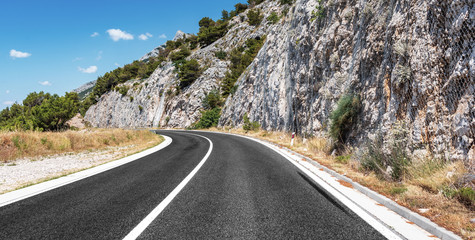 Mountain highway with blue sky and rocky mountains on a background
