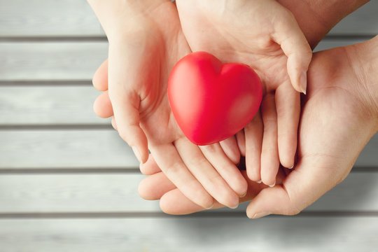 Man and woman holding red heart on background