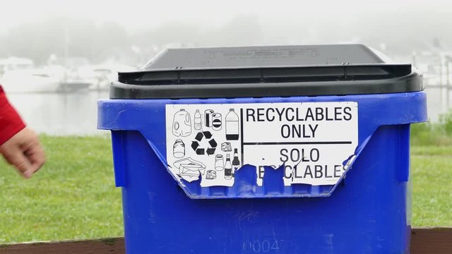 Man is adding plastic bottle to recycling bin