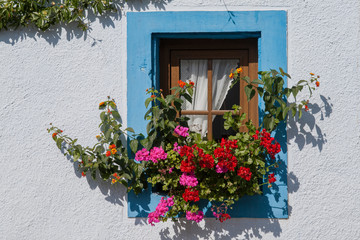 Fototapeta na wymiar Kleines Fenster mit Blumenschmuck