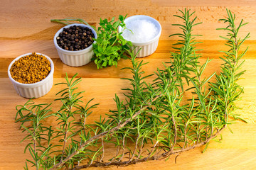 Different spices, rosemary, thyme, pepper, salt and steak rub for bbq on a wooden board, kitchen background.
