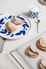 Delicious homemade dessert on blue plates. Shortbread sweet with coffee in a white mug. teaspoon golden. Saucer with earrings of leaves. On a white background.