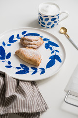 Delicious homemade dessert on blue plates. Shortbread sweet with coffee in a white mug. teaspoon golden. Saucer with earrings of leaves. On a white background.