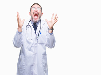 Middle age senior hoary doctor man wearing medical uniform isolated background celebrating mad and crazy for success with arms raised and closed eyes screaming excited. Winner concept