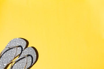Silver flip flops on a yellow background. Top view, flat lay