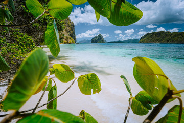 Fototapeta na wymiar Tropical beach scenery with rocky islands and impressive clouds, framed with lush vegetation. Exploring Philippines, Palawan