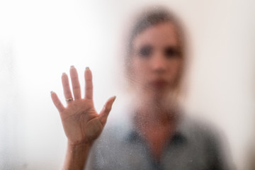 Woman behind a frosted glass. The concept of female fears, depression, despair, hopelessness.