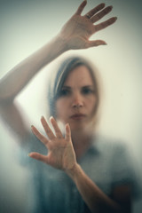 Woman behind a frosted glass. The concept of female fears, depression, despair, hopelessness.