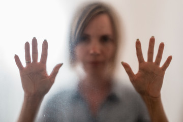 Woman behind a frosted glass. The concept of female fears, depression, despair, hopelessness.
