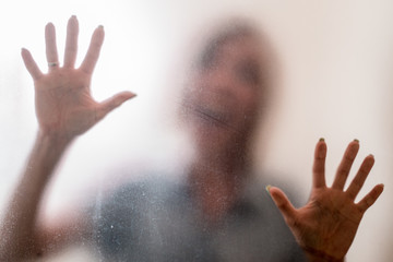 Woman behind a frosted glass. The concept of female fears, depression, despair, hopelessness.