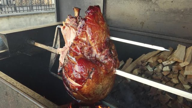 Whole piece of pork leg rotates in the grill. Prague ham street food
