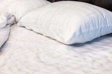 Two white pillows with white bedding sheet on empty bed in bedroom for rest and relax in the morning