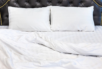 Two white pillows with white bedding sheet on empty bed in bedroom for rest and relax in the morning