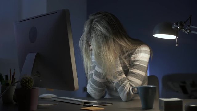 Stressed woman at desk with head in hands