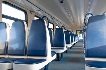 Fototapeta premium Rows of blue soft seats in a passenger train car. Bright sun shines through the window. Without people.