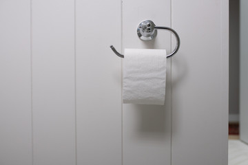 White toilet tissue against a white timber wall