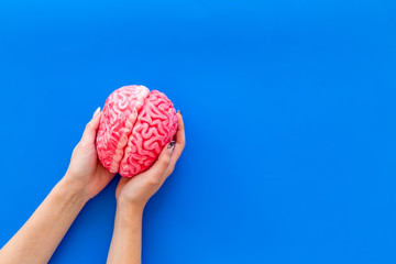 Brainstorm concept with brain in hands on blue background top view mockup