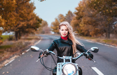 Fototapeta na wymiar Stylish biker woman with motorcycle on the road.