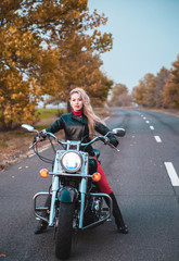 Stylish biker woman with motorcycle on the road.