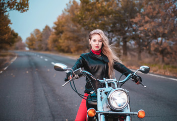 Obraz na płótnie Canvas Stylish biker woman with motorcycle on the road.