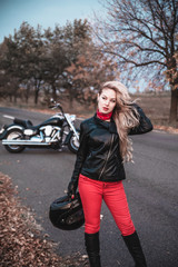 Stylish biker woman with motorcycle on the road.