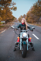 Fototapeta na wymiar Stylish biker woman with motorcycle on the road.