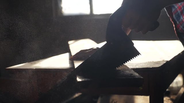 carpenter handmade and craft concept slow motion video. carpenter sawing a tree in a workshop sawing sunlight from a window lifestyle silhouette. woodworker engaged handmade in processing wood at the