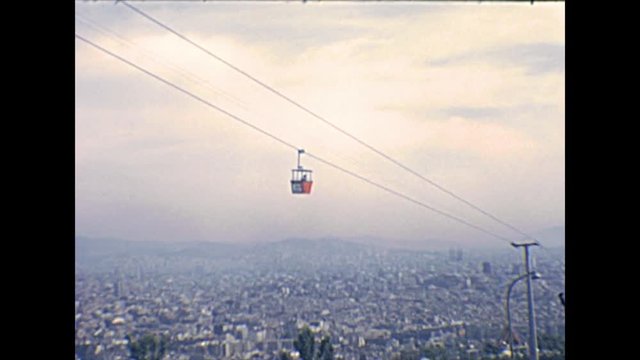 cableway moving on top of skyline of Barcelona city from the Montjuic Castle, an old military fortress of Catalonia region overlooking Barcelona. Historical archival of aerial view of Spain in 1970s.