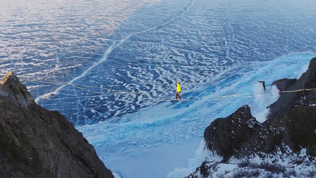 Tightrope Walker on the background of blue ice frozen lake.