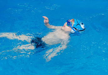 little boy learns to swim in the pool