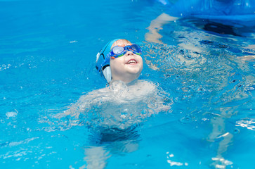 little boy learns to swim in the pool