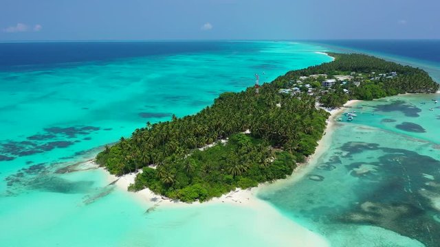 tropical island in Philippine Sea with coconut palms, with crystal clear water showing corals on seafloor aerial drone parallax establishing shot