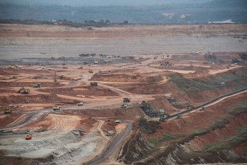 Lignite coal mining industry as a raw materials for coal fire electric power plant. There are excavators and transport trucks are working within the lignite coal mine.