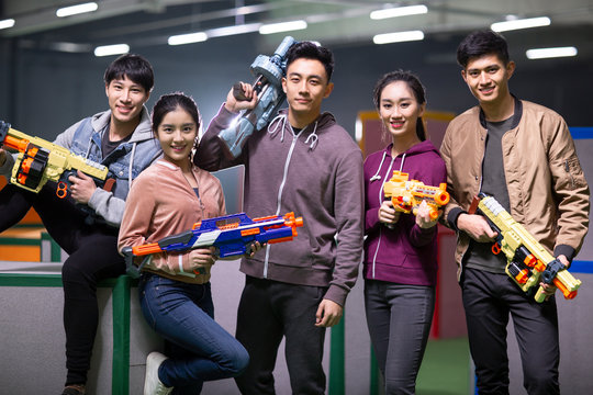Happy young friends playing gun game